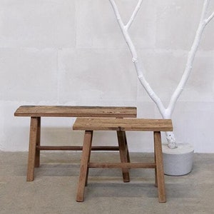 Puede incluir: Dos bancos de madera con una rama pintada de blanco en el fondo. Los bancos están hechos de madera natural y tienen un aspecto rústico.