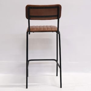 May include: A brown leather bar stool with a black metal frame. The backrest and seat are padded and stitched. The stool has a minimalist design, suitable for a kitchen or bar setting.