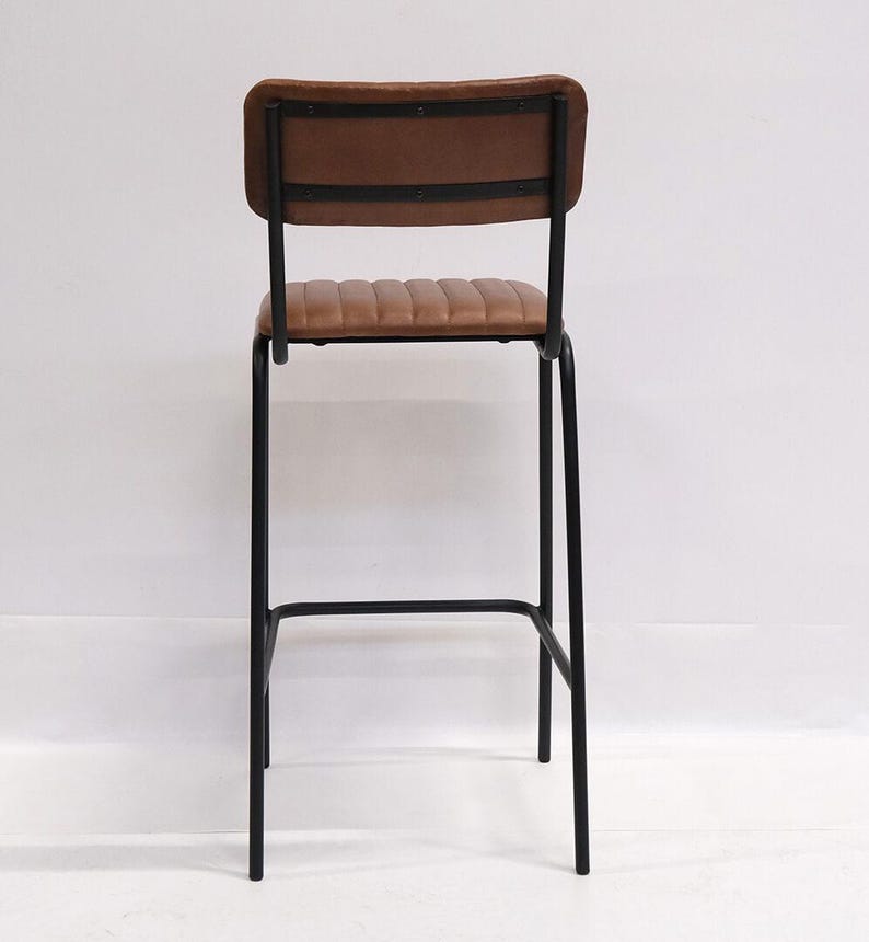 May include: A brown leather bar stool with a black metal frame. The backrest and seat are padded and stitched. The stool has a minimalist design, suitable for a kitchen or bar setting.