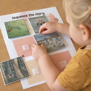 May include: A child is arranging picture cards on a worksheet labeled "Sequence the story." The cards depict scenes from a story, with illustrations of people in various settings. The worksheet has pink and beige squares with velcro.