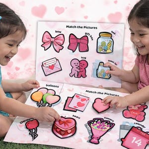 Op de afbeelding: Twee jonge kinderen spelen een Valentijnsdag-zoekspel. Het spel bevat illustraties van strikken, harten en andere gerelateerde afbeeldingen. De tekst "Match the Pictures" is zichtbaar op het spelbord.