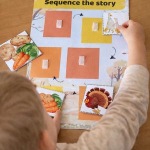 May include: A child's educational game with the text "Sequence the story". The game features a board with colored squares and picture cards of vegetables, a turkey, and a family of geese. The child is interacting with the game.