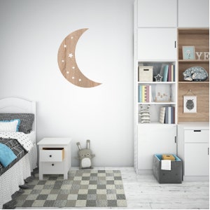 May include: A white wooden nightstand with two drawers, a white wooden bed frame with a white and black patterned duvet, a gray and white checkered rug, a white bookcase with shelves filled with books and toys, a gray storage bin, and a wooden crescent moon wall decor with white stars.