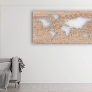 May include: A light wood wall decor with a cutout of the world map. The map is in a light brown color and the background is a light wood color. The decor is hanging on a white wall in a living room setting.