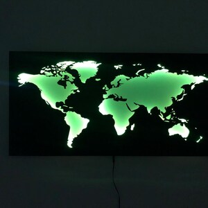 May include: A black metal world map wall decor with a green light shining through the cut-out continents.