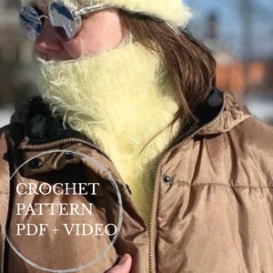May include: A pale yellow fuzzy crochet neck warmer worn with a tan puffer jacket. The image features a circular overlay with the white text CROCHET PATTERN PDF + VIDEO. The neck warmer has a soft, textured, and fibrous appearance.