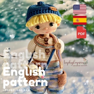 Puede incluir: Patrón de amigurumi de crochet para un muñeco de niño que lleva un gorro azul, un suéter marrón y pantalones a rayas. El muñeco lleva un pequeño animal de crochet. El patrón está disponible en inglés y español. La imagen también incluye el texto "English pattern" y "Loopybyloopsan Amigurumi Designer".