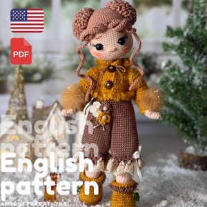 Puede incluir: Muñeca de ganchillo hecha a mano con un diseño detallado. La muñeca viste una chaqueta amarillo mostaza con botones marrones, pantalones marrones y un sombrero a juego. La muñeca tiene la piel clara, mejillas rosadas y ojos negros. El texto "English pattern" es visible.