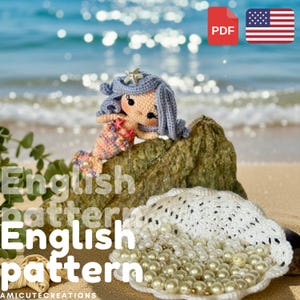 Peut inclure: Une poupée sirène crochetée avec des cheveux bleu pervenche, un visage couleur pêche et une queue multicolore ornée d'étoiles de mer roses. La poupée repose sur un rocher à côté d'un bol en forme de coquillage crocheté rempli de perles blanches.