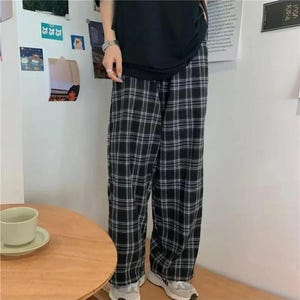 May include: Black and white plaid pants with a wide leg silhouette. The pants are made of a soft, comfortable fabric and have a relaxed fit.