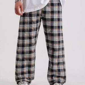 May include: Black and tan plaid pants with a relaxed fit. The pants have a drawstring waistband and are made of a soft, comfortable fabric.