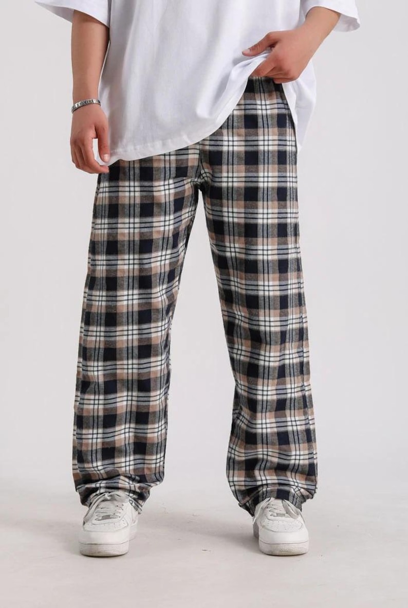 May include: Black and tan plaid pants with a relaxed fit. The pants have a drawstring waistband and are made of a soft, comfortable fabric.