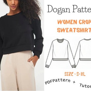 May include: A black cropped sweatshirt with long sleeves and a round neckline. The image also shows a line drawing of the sweatshirt in white with a grey hem, and the text "Dogan Pattern Women Crop Sweatshirt Size: S-XL PDF Pattern + Tutorial!"