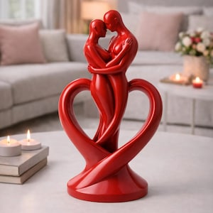 May include: A red sculpture of two embracing figures, forming a heart shape at the base. The figures are intertwined, with their heads touching. The sculpture is a decorative item, likely for a home setting.