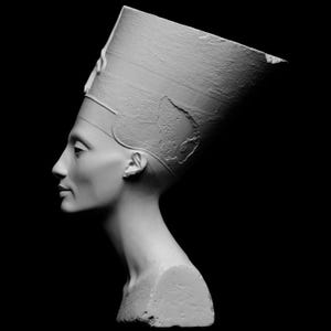 May include: A white plaster bust of an Egyptian queen wearing a traditional headdress. The bust is sculpted in a realistic style and shows the queen's face in profile.