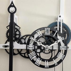 May include: A wall clock with exposed gears and Roman numerals. The clock features a black and white color scheme, with a circular clock face and intricate gear mechanisms. The clock's hands are white, and the gears are black and blue.