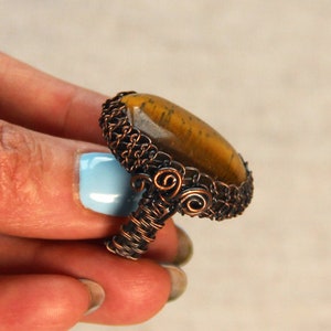 Könnte beinhalten: Ein Ring aus Kupferdraht mit einem braunen Tigerauge-Stein.