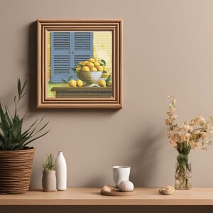 Puede incluir: Una pintura enmarcada de un bodegón con limones en un cuenco, una ventana azul con contraventanas y una mesa de madera. La pintura está colocada sobre una pared de color marrón claro.