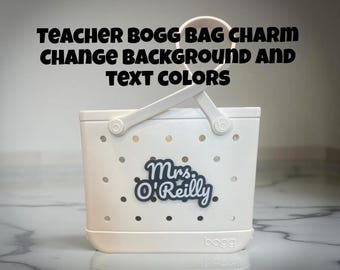 Può includere: Una borsa tote bianca con manico e la scritta "Teacher Bogg Bag Charm Change Background and Text Colors". La borsa ha un'etichetta con il nome di Mrs. O'Reilly. La borsa ha diversi piccoli fori.