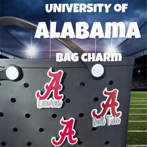 May include: Three red and white University of Alabama "A" charms with the words "Roll Tide" and "Lauren" on two of them. The charms are attached to a black tote bag.