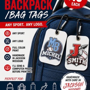 May include: Two rectangular white bag tags with black carabiners attached to a navy blue backpack. The left tag features a baseball graphic with the text MB MICHEL. The right tag displays a large letter J, a baseball, and the text SMITH.
