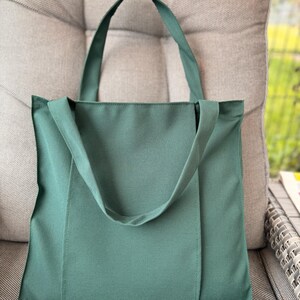 Dark green tote bag on the gray ottoman.