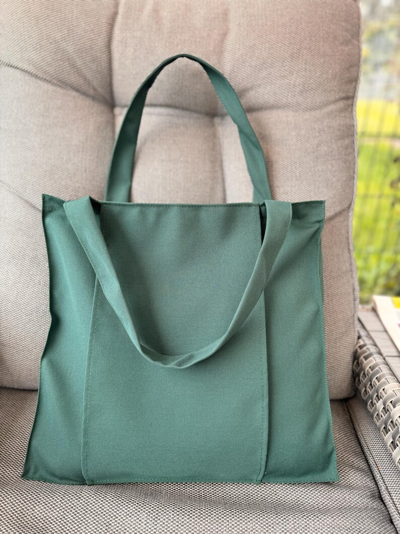 Dark green tote bag on the gray ottoman.