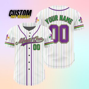 K&ouml;nnte beinhalten: Wei&szlig;es Baseballtrikot mit lila und gr&uuml;nen Streifen. Die Vorderseite des Trikots tr&auml;gt den Text "Mardi Gras" und die Nummer "00". Die R&uuml;ckseite des Trikots tr&auml;gt den Text "YOUR NAME" und die Nummer "00".