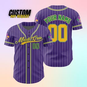 K&ouml;nnte beinhalten: Lila und wei&szlig; gestreiftes Baseballtrikot mit gelben und gr&uuml;nen Akzenten. Die Vorderseite des Trikots tr&auml;gt den Text "Mardi Gras" und die Nummer "00". Die R&uuml;ckseite des Trikots tr&auml;gt den Text "YOUR NAME" und die Nummer "00".