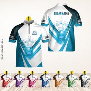 May include: A white bowling jersey with a blue and black design featuring a bowling ball and pins. The jersey has a zippered collar and the text "TEAM NAME" on the back. The jersey is available in a variety of colors.