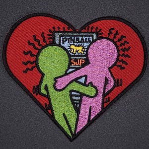 May include: Embroidered patch in the shape of a red heart with two green and pink figures holding hands in front of a pinball machine that says "PINBALL" and "SUP".