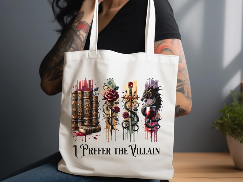 Pode incluir: Sacola de tecido branca com um design colorido que apresenta uma pilha de livros, uma espada, uma rosa, um drag&atilde;o e uma ta&ccedil;a de vinho. O texto "I Prefer the Villain" est&aacute; impresso na sacola.