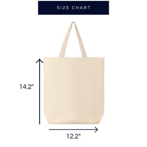 Pode incluir: Uma bolsa tote de lona branca lisa com duas al&ccedil;as. A bolsa mede 14,2 polegadas de altura e 12,2 polegadas de largura.