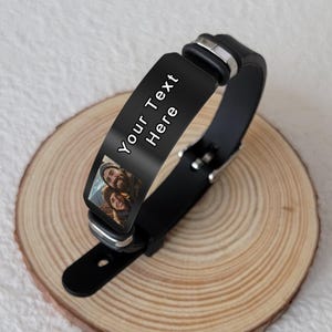 May include: Black silicone bracelet with a black metal plate that has a photo of a couple and the text "Your Text Here" in white.