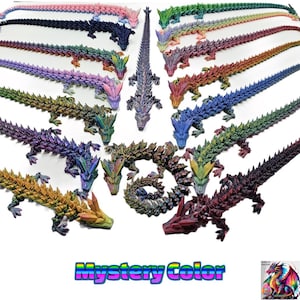 May include: A collection of 17 iridescent, multi-coloured, 3D printed dragon figurines. Each dragon is posed in a different position, with its tail curled around its body. The dragons are all made of a shiny, reflective material. The text "Mystery Color" is written in rainbow letters at the bottom of the image.
