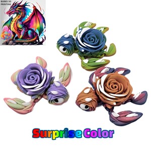 Könnte beinhalten: Drei bunte Schildkrötenfiguren mit Blumen auf dem Rücken. Die Schildkröten sind aus Polymer Clay gefertigt und haben einen verspielten, handgefertigten Look. Die Blumen sind in den Farben Lila, Blau und Braun.