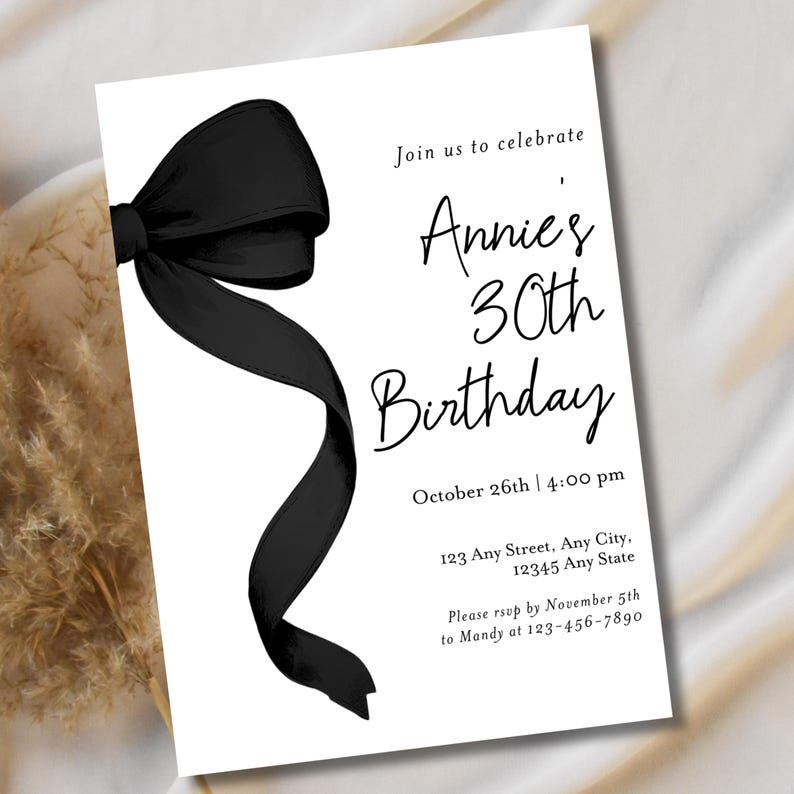 May include: Black and white birthday invitation with a black bow on the left side. The invitation reads "Join us to celebrate Annie's 30th Birthday" with the date and time "October 26th | 4:00 pm" and the address "123 Any Street, Any City, 12345 Any State". The RSVP information is "Please RSVP by November 5th to Mandy at 123-456-7890".