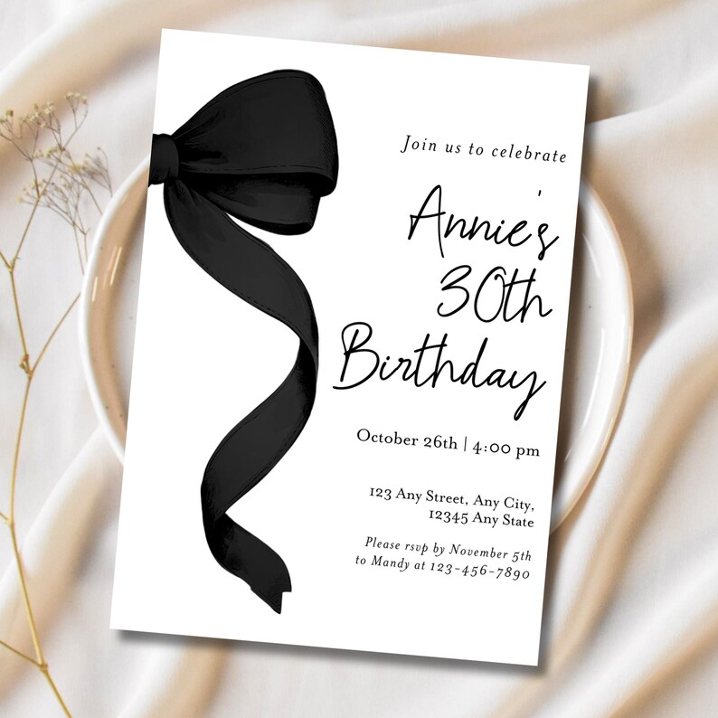 May include: Black and white birthday invitation with a black bow on the left side. The text reads "Join us to celebrate Annie's 30th Birthday, October 26th | 4:00 pm, 123 Any Street, Any City, 12345 Any State, Please RSVP by November 5th to Mandy at 123-456-7890."
