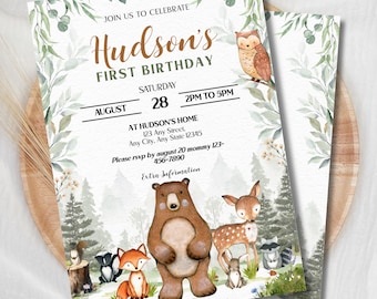 May include: A rectangular birthday invitation card featuring watercolor illustrations of a bear, deer, fox, owl, raccoon, and squirrel in a forest. The text reads: JOIN US TO CELEBRATE Hudson's FIRST BIRTHDAY SATURDAY AUGUST 28 2PM TO 5PM AT HUDSON'S HOME.