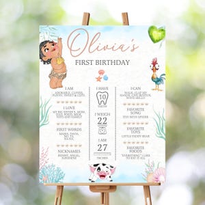 May include: A rectangular birthday milestone sign featuring the text Olivia's FIRST BIRTHDAY, illustrated with a cartoon baby, a rooster, and a piglet. The sign includes sections for teeth, weight of 10 kg, and height of 69 cm, with sea-themed accents.