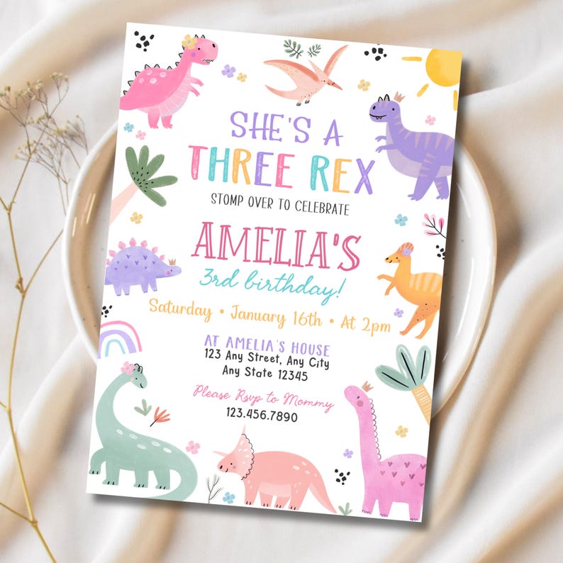May include: A colorful birthday invitation with dinosaur illustrations. The text reads "She's a Three Rex" and "Amelia's 3rd birthday!" with details for the party. The design includes a rainbow, sun, and various dinosaur characters in pink, purple, and green.