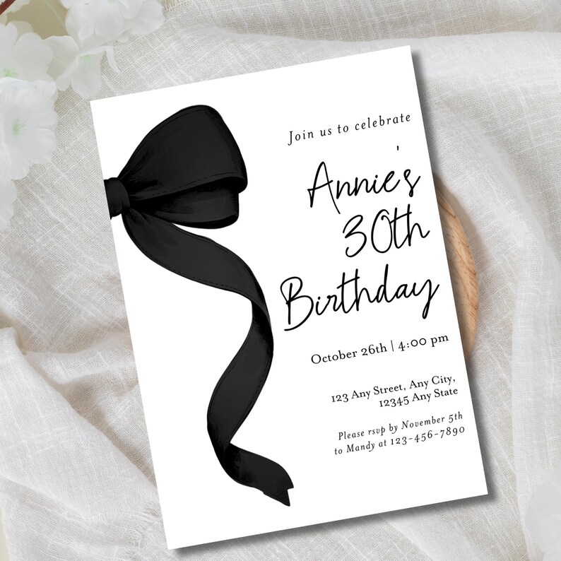 May include: Black and white birthday party invitation with a black bow on the left side. The invitation reads "Join us to celebrate Annie's 30th Birthday" with the date and time "October 26th | 4:00 pm" and the address "123 Any Street, Any City, 12345 Any State". The RSVP information is "Please rsvp by November 5th to Mandy at 123-456-7890".