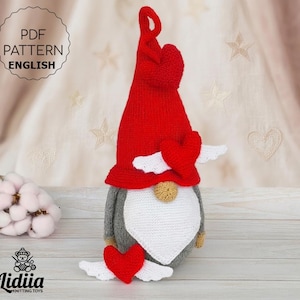 May include: A handmade knitted gnome doll with a red hat and heart accents. The gnome has a gray body, white beard, and a small, tan nose. The image includes the text "PDF PATTERN ENGLISH" and the logo "Lidiia Knitting Toys".