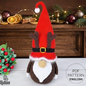 Puede incluir: Un gnomo navideño hecho a mano con un gorro rojo, cuernos marrones y barba blanca. El gnomo lleva un cinturón negro con hebilla dorada. El gnomo es un juguete de punto. La imagen incluye el texto "PDF PATTERN ENGLISH".
