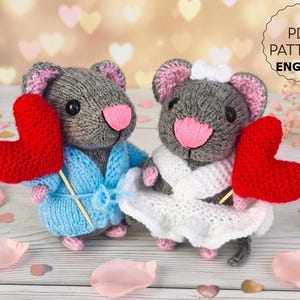 May include: Two grey knitted mice, one in a blue robe and the other in a white dress, each holding a red heart. The mice have pink ears and noses. The image includes the text "PDF PATTERN ENGLISH".