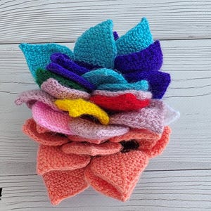 Brightly colored knitted flower mats folded together and stored inside a small handknit basket.