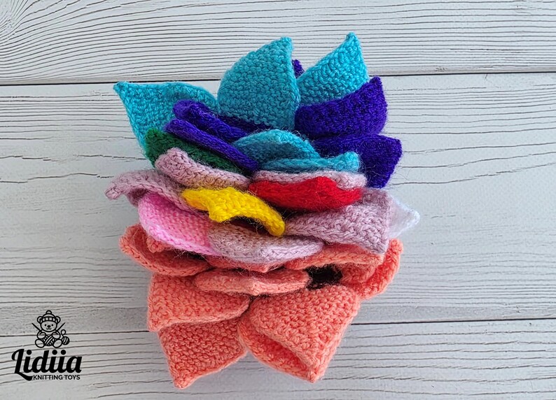 Brightly colored knitted flower mats folded together and stored inside a small handknit basket.