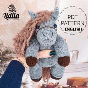 May include: A knitted horse toy in grey and brown, featuring a fluffy brown mane and dark brown hooves. The toy has a halter. The image includes the text "PDF PATTERN ENGLISH" and the Lidiia Knitting Toys logo.