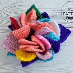 Brightly colored knitted flower mats folded together and stored inside a small handknit basket.