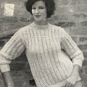 May include: A black and white photo of a woman wearing a white knitted sweater with a cable knit pattern. The sweater is from Jaeger and is made of Spiral-Spun yarn. The photo is from a knitting pattern book and includes the number 3648.